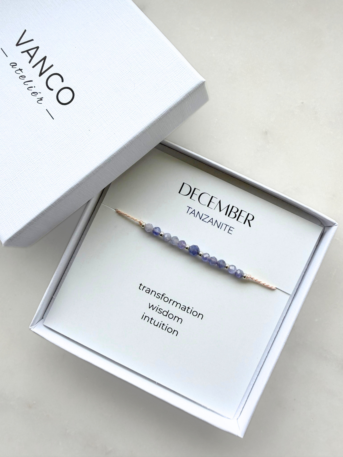 White gift box with a tanzanite bracelet. The bracelet is put on a card titled "December Tanzanite". 