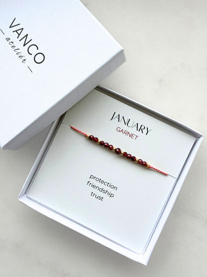 White gift box with a garnet bracelet. The bracelet is put on a card titled "January Garnet". 