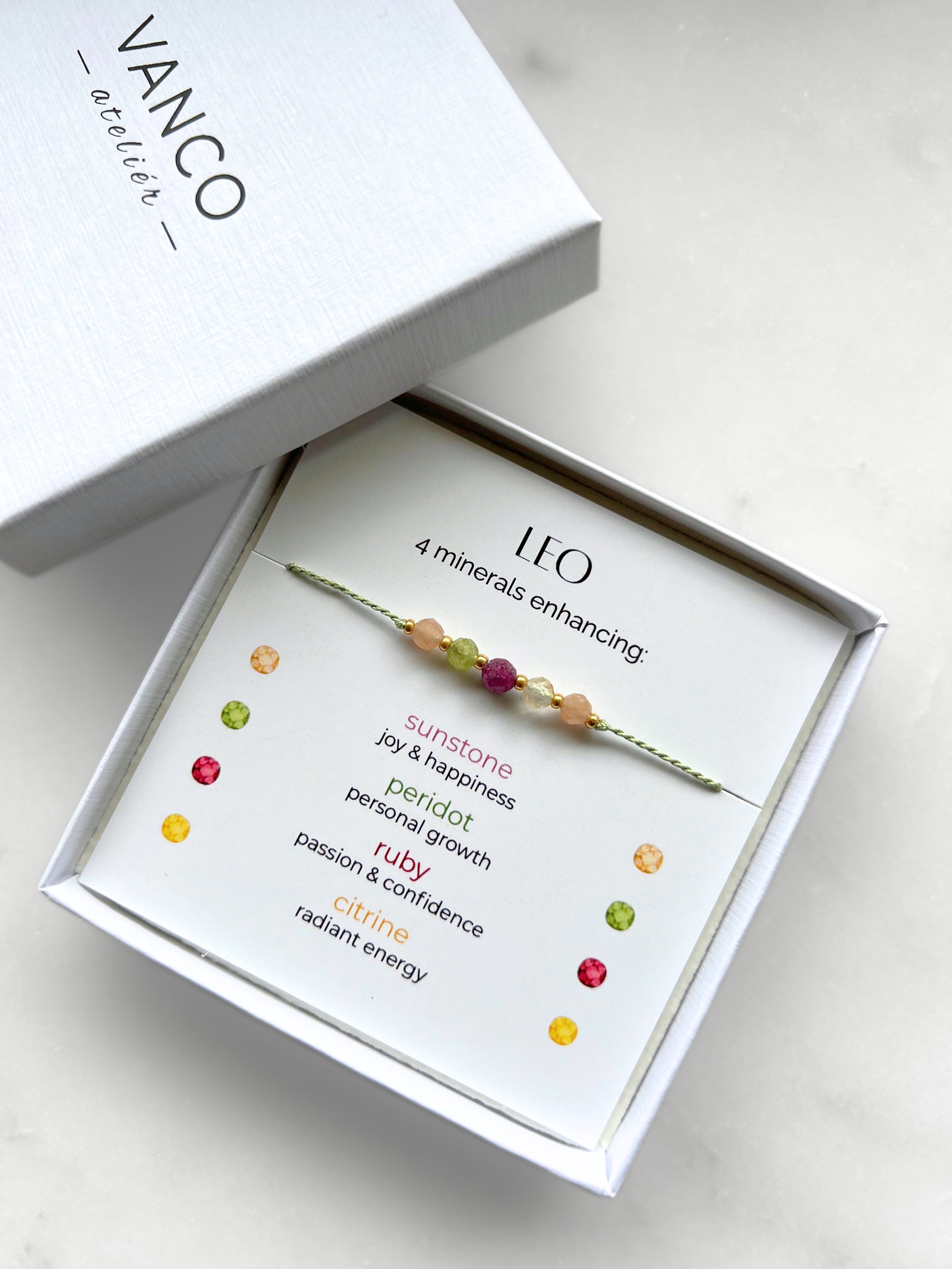 White gift box that contains a mineral bracelet for a Leo Zodiac sign. The bracelet is displayed on a card that describes the minerals and their meanings. There are five minerals on the bracelet: two sunstones, peridot, ruby and citrine