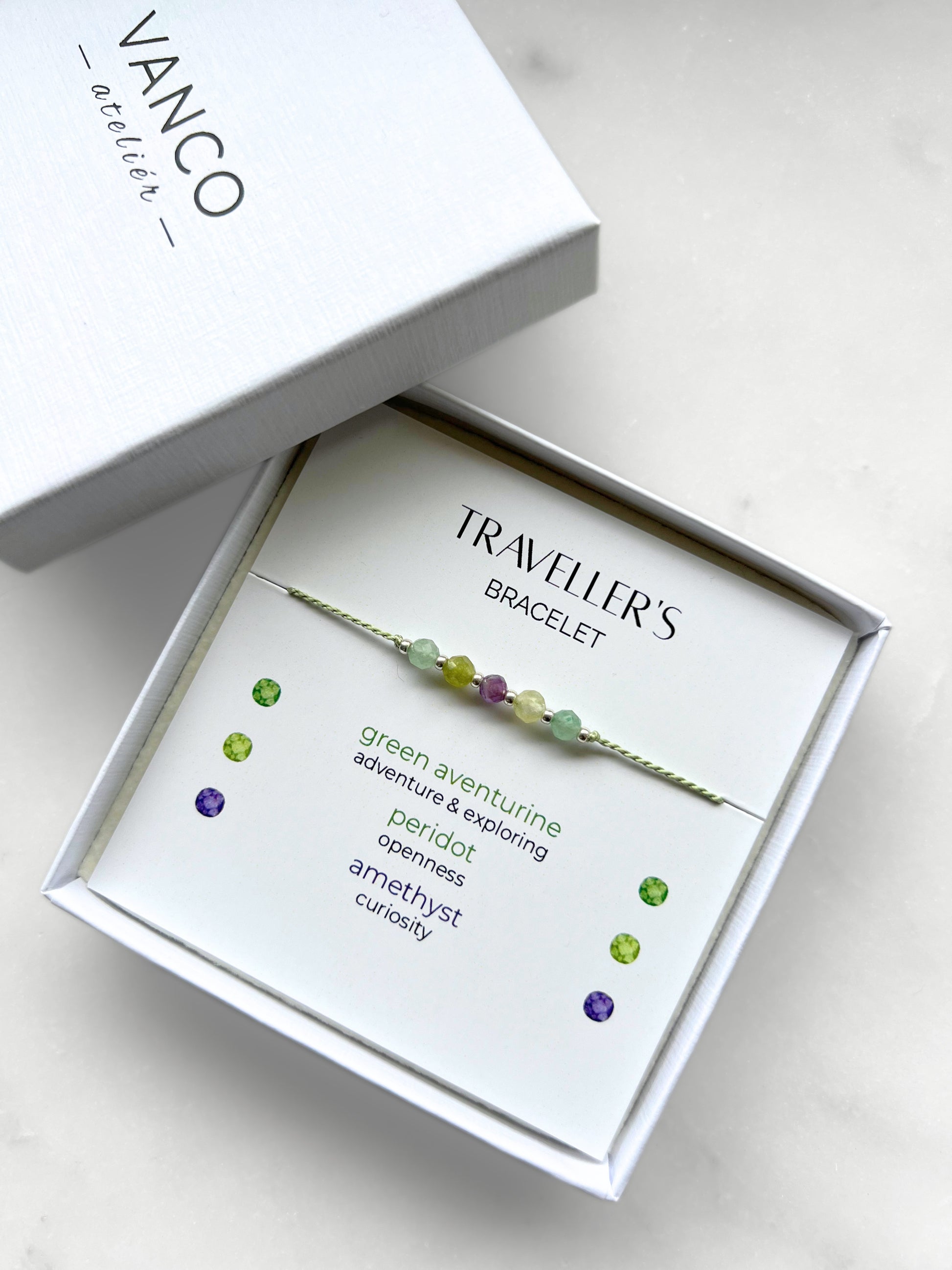 Green silk cord bracelet with natural crystals in a white gift box, titled Traveller's Bracelet.