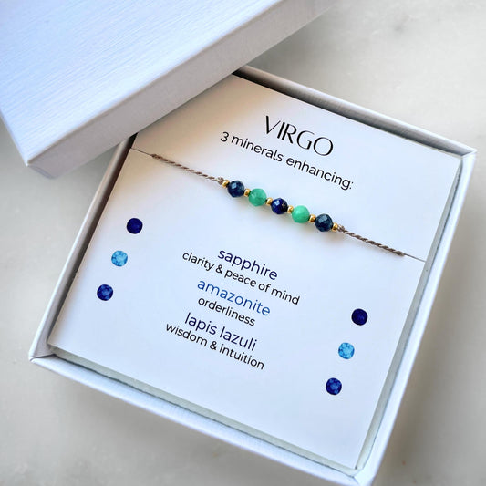 White gift box that contains a mineral bracelet for a Virgo Zodiac sign. The bracelet is displayed on a card that describes the minerals and their meanings. There are five minerals on the bracelet: two sapphires, two amazonites and one lapis lazuli
