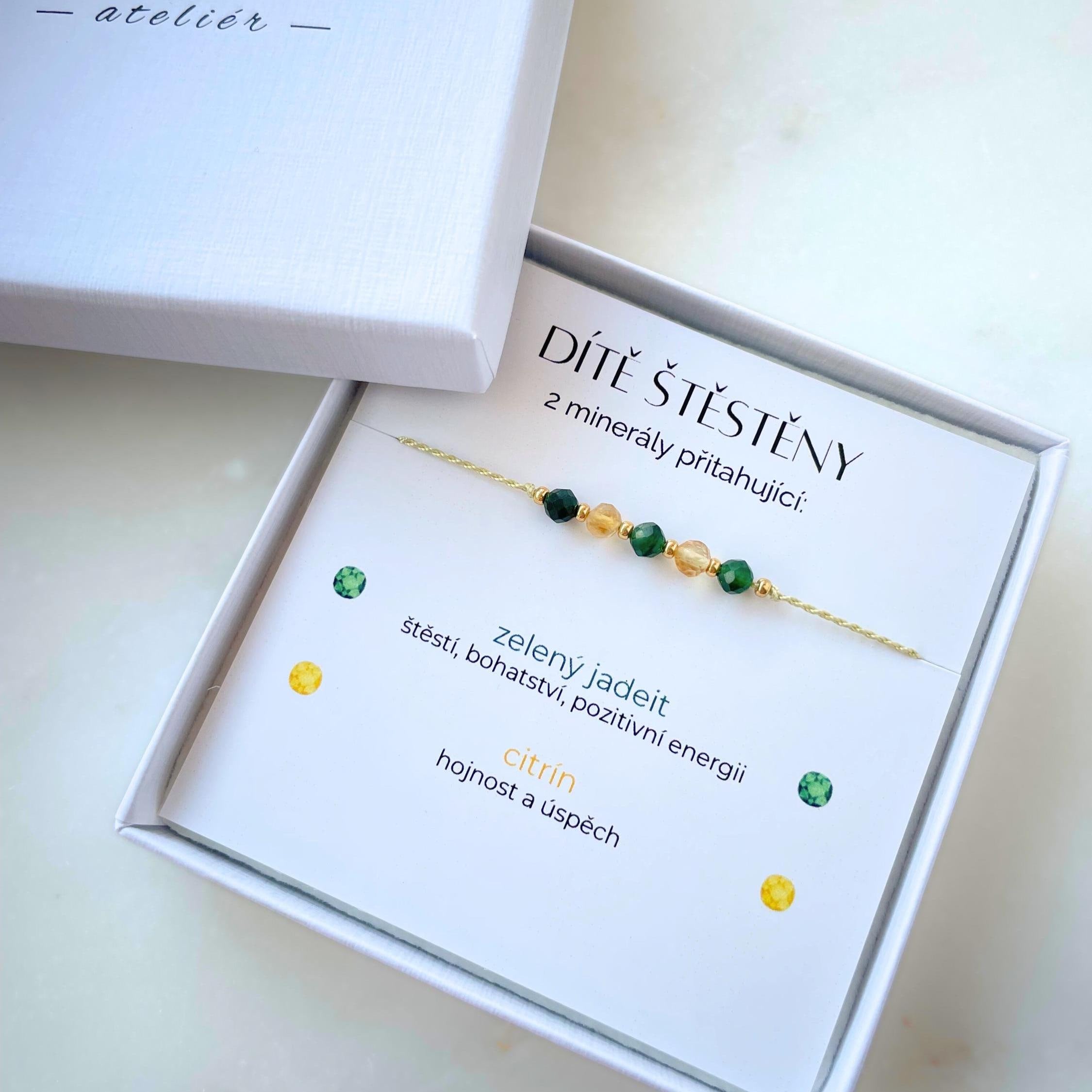 Bílá krabička, ve které je náramek vytvořený z hedvábného provázku a pěti minerály. Náramek je upevněn na promo kartičce s nápisem Dítě Štěstěny. Náramek je udělán na téma Štěstí. Karta také obsahuje vysvětlivky ke každému použitému kameni: Zelený Jadeit pro Štěstí, Bohatství a Pozitivní Energii, Citrín pro Hojnost a Úspěch