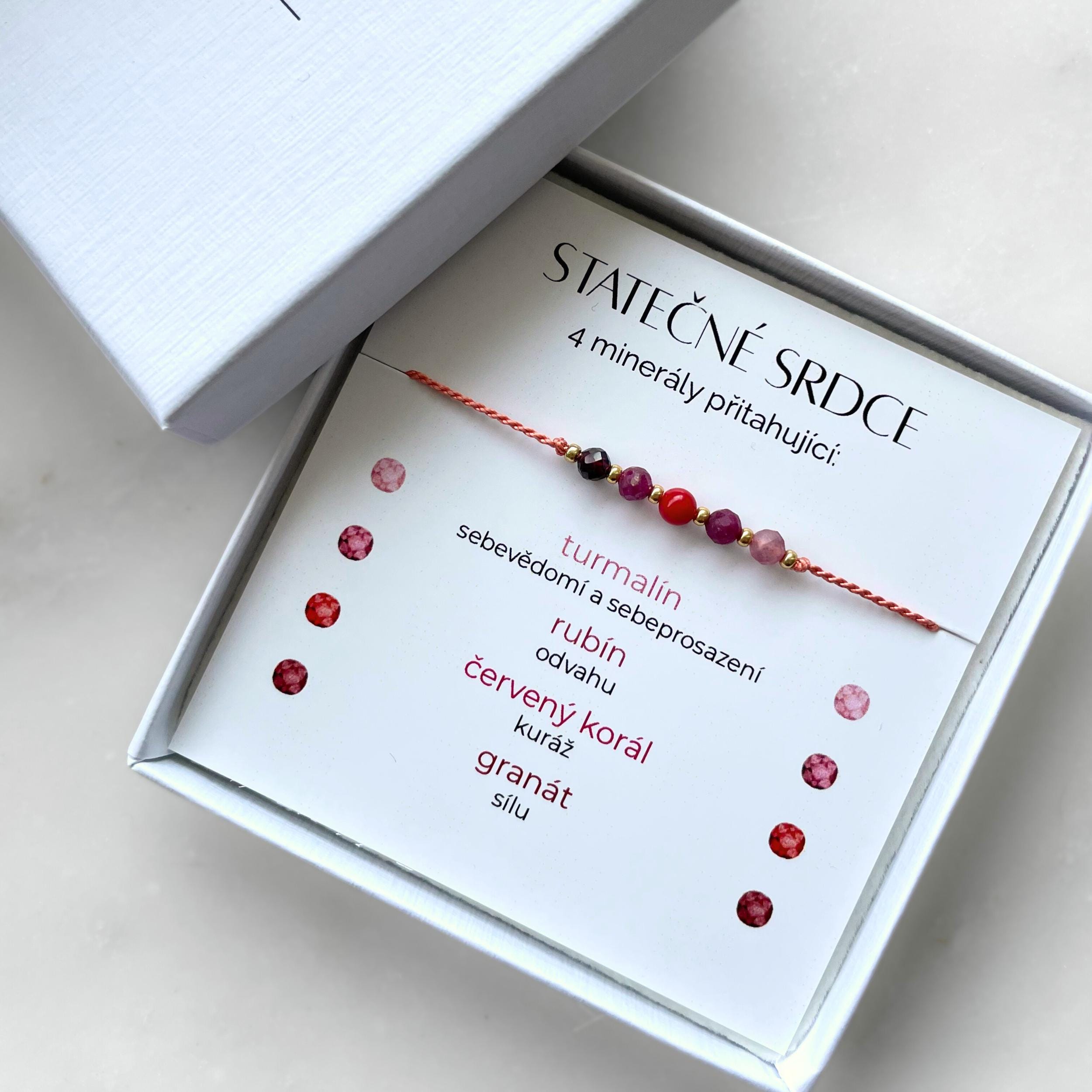 Náramek z hedvábného provázku s pěti minerály v dárkové krabičce. Součástí balení je kartička s nápisem Statečné Srdce a s vysvětlivkami ke každému kameni: Červený korál pro kuráž, rubín pro odvahu, granát pro sílu, turmalín pro sebevědomí a sebeprosazení